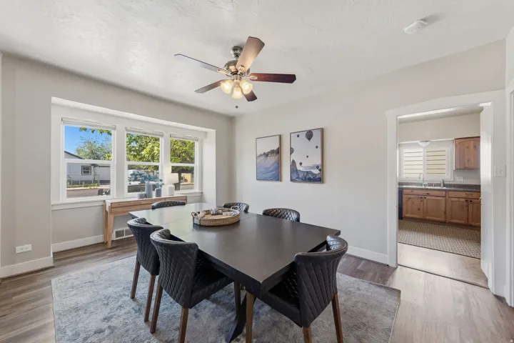 Dining area featuring wood-finish flooring, a contemporary ceiling fan with integrated lighting, and a multi-paned window