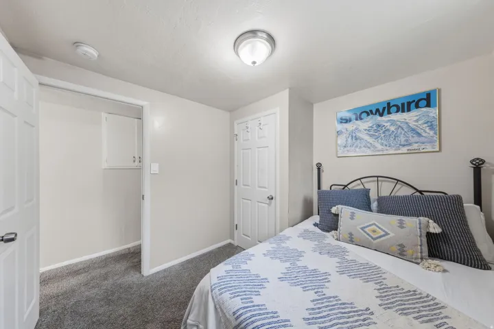 Bedroom featuring neutral wall paint, gray carpet, a white paneled door, and a built-in closet with upper cabinetry