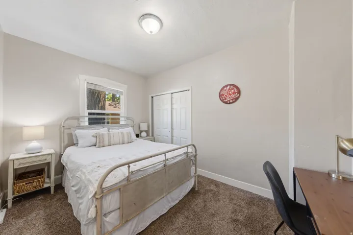 Bedroom featuring soft neutral wall paint, a window with exterior views, and a dual-door closet with white bifold doors