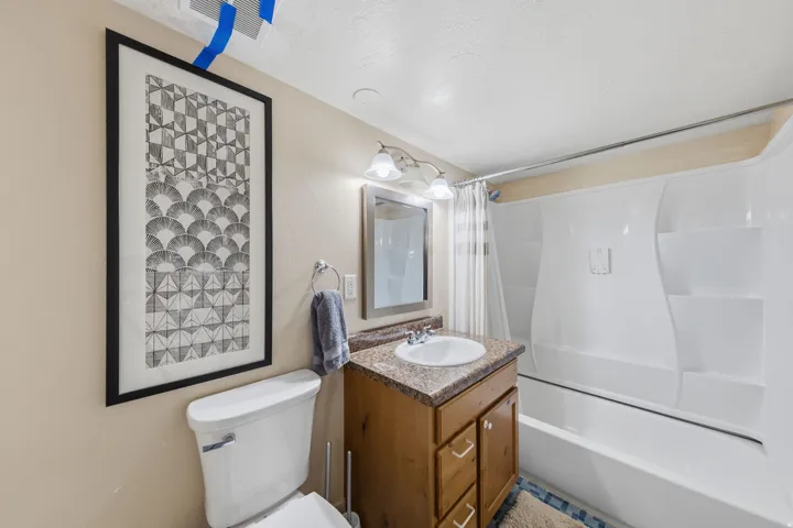 Bathroom featuring a single vanity with wood-finish cabinetry, a speckled countertop, and a white basin