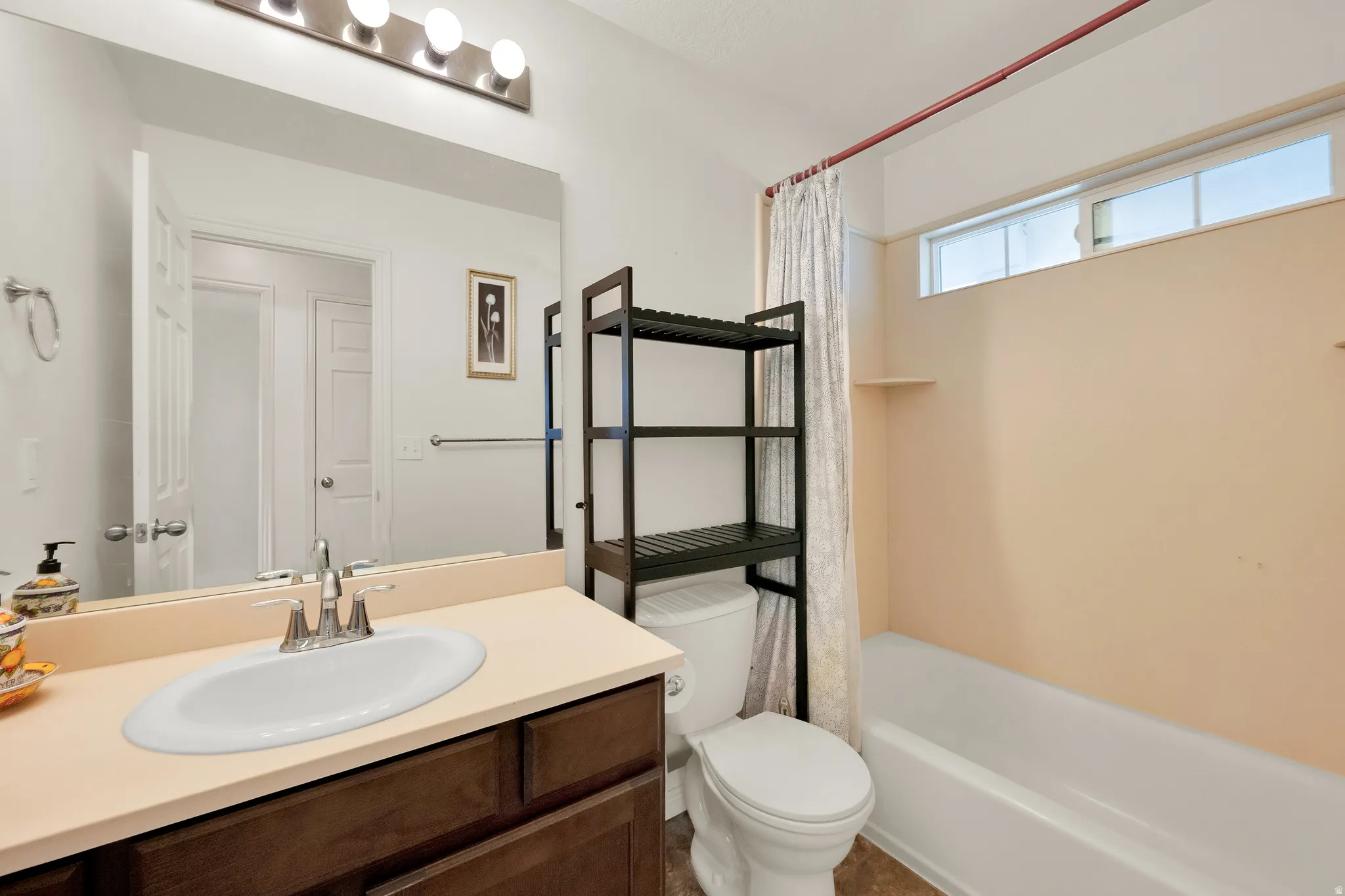 Bathroom featuring a single vanity with a light-colored countertop, an undermount sink, and a chrome faucet