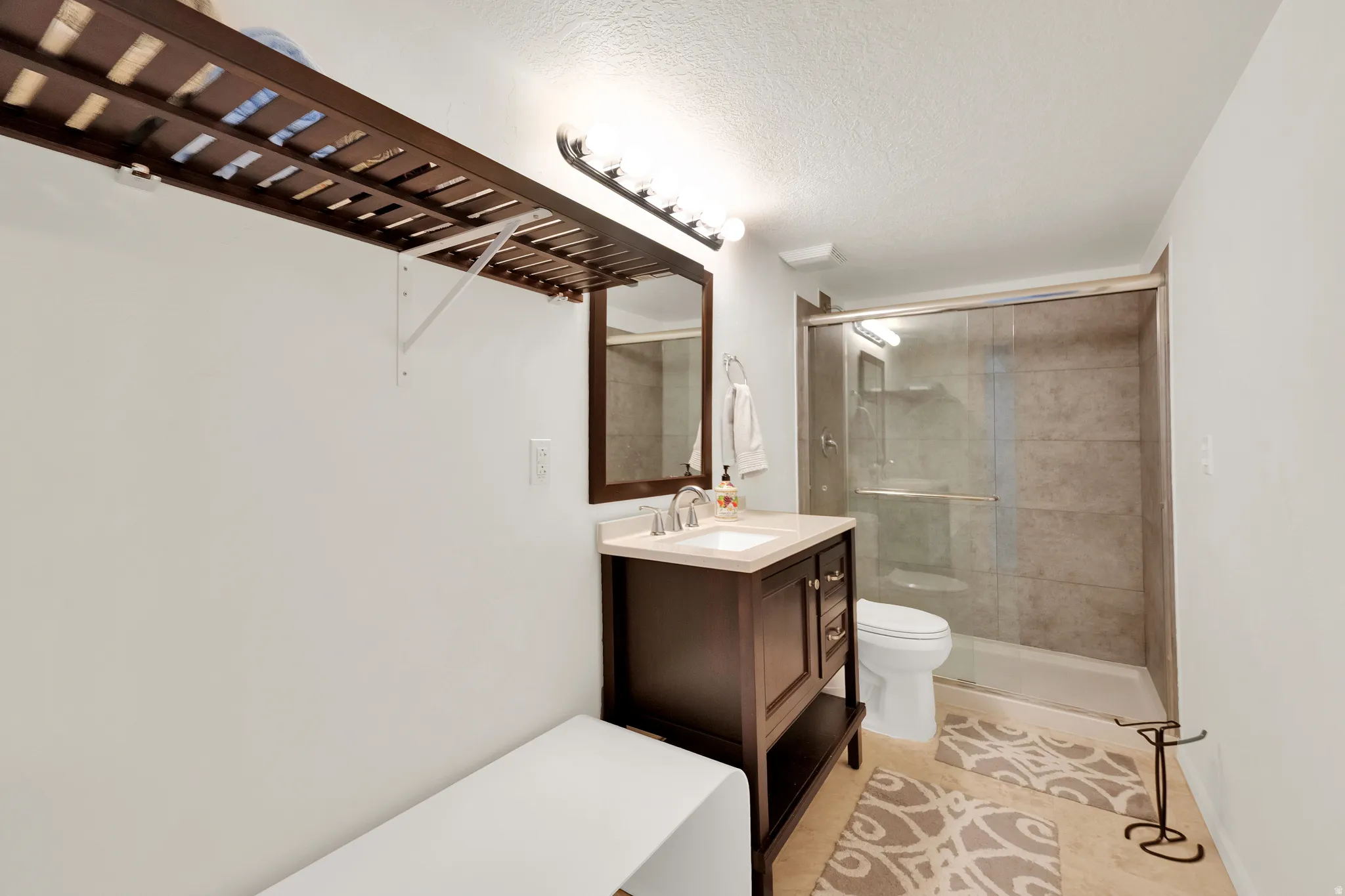 Bathroom featuring a dark wood-finish vanity with a light countertop, a rectangular mirror, and a shower with sliding glass doors