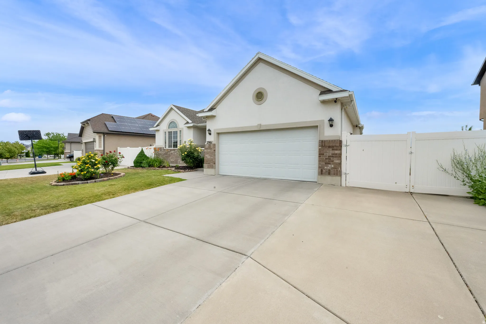 Stucco exterior featuring a two-car garage, an arched window, and decorative brick accents