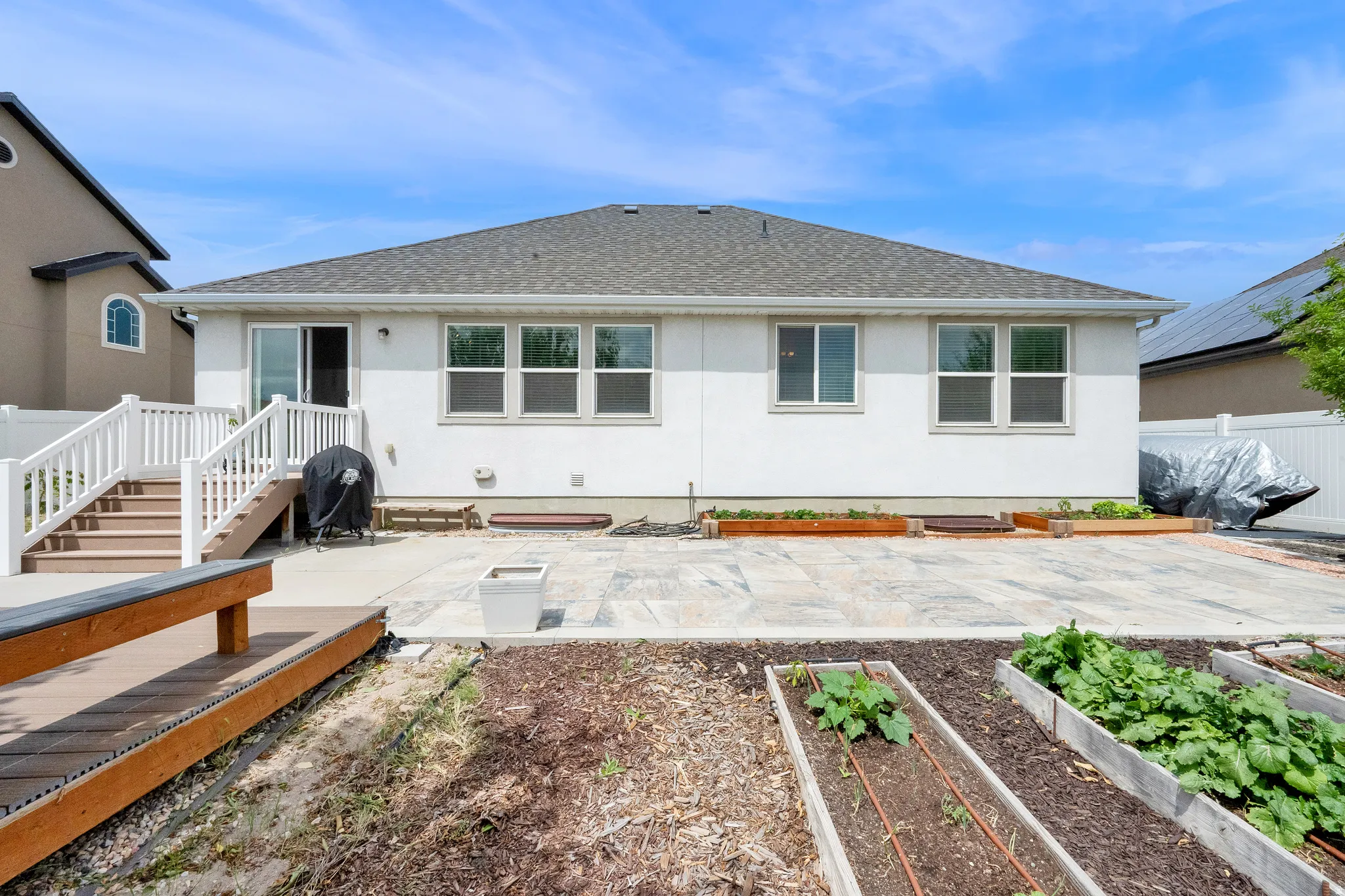 Rear exterior featuring a white stucco facade, a private patio, and a multi-level deck with white railings