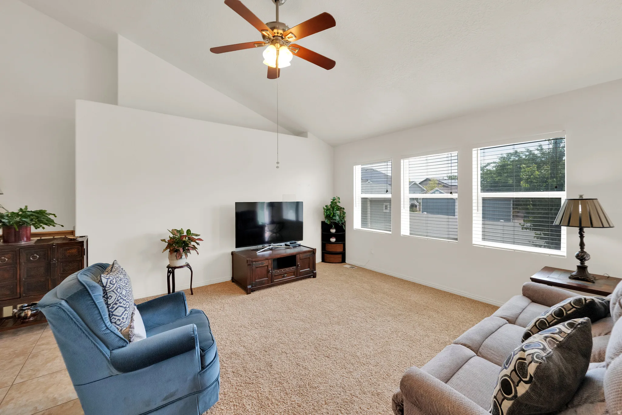 Spacious living area featuring a vaulted ceiling and a ceiling fan with integrated lighting