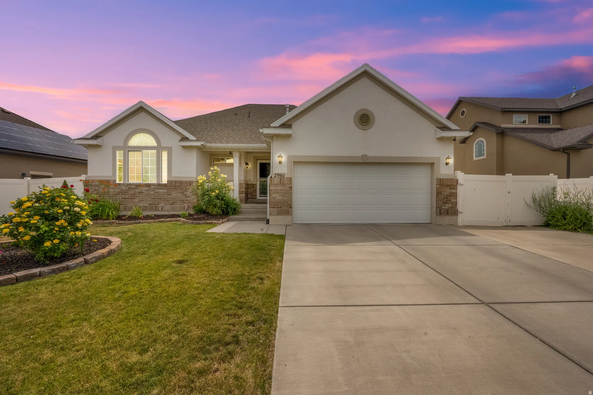 Modern stucco and stone-veneer exterior with an arched window, a two-car garage, and a concrete driveway
