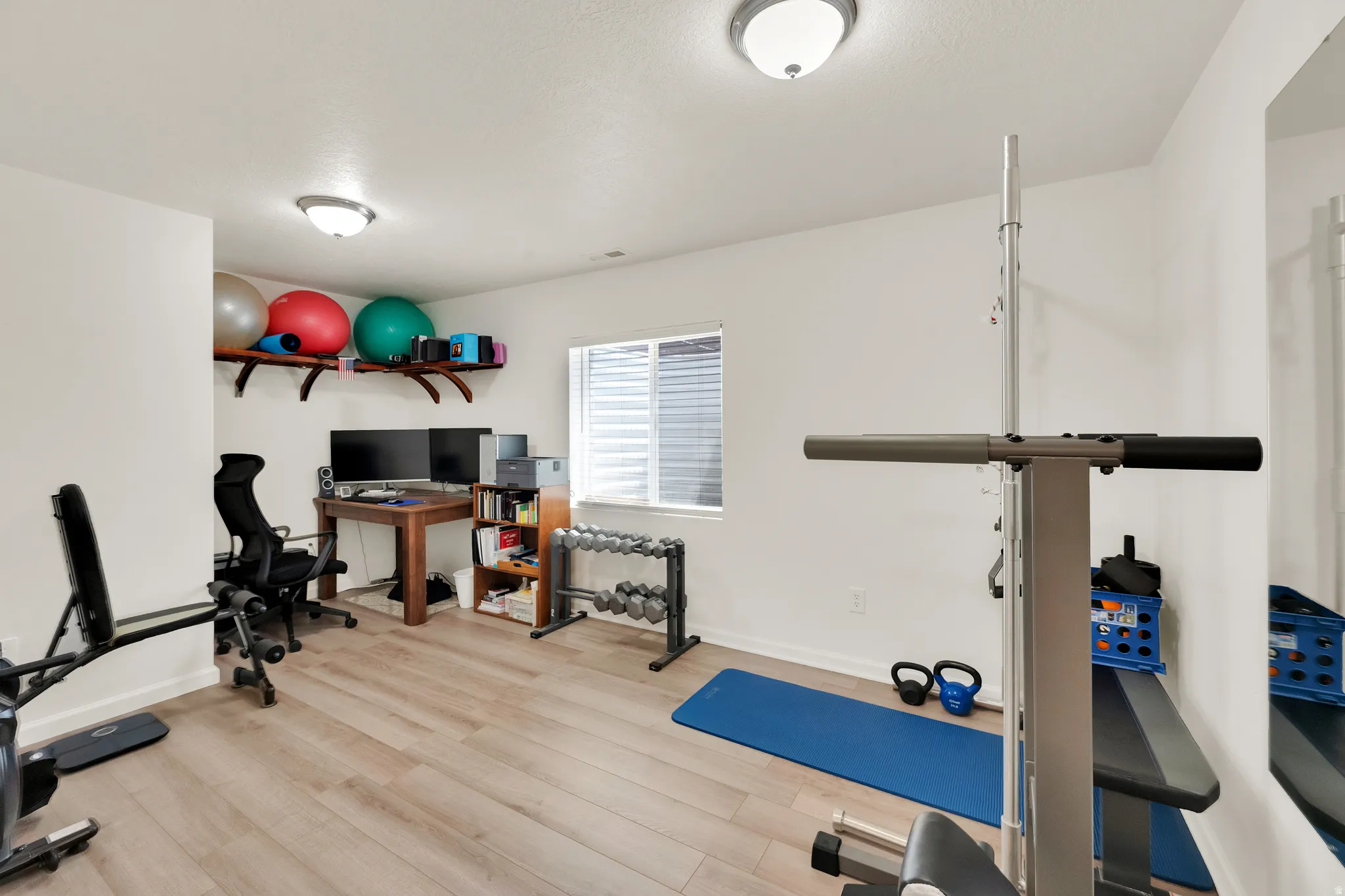 Versatile multi-purpose room featuring wood-finish flooring, recessed lighting, and a window with horizontal blinds
