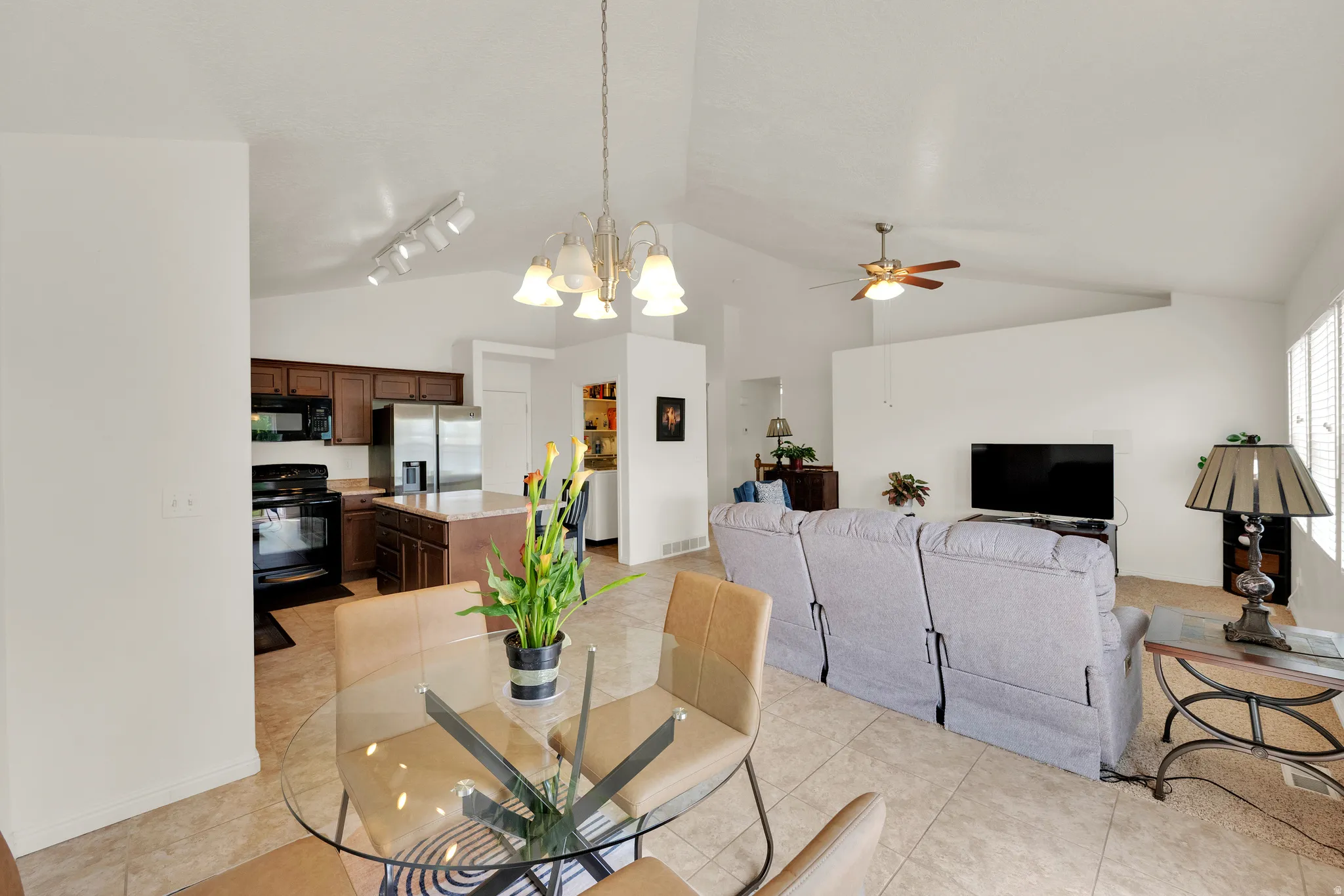 Open-concept living space featuring vaulted ceilings, tile flooring, and integrated kitchen and dining areas