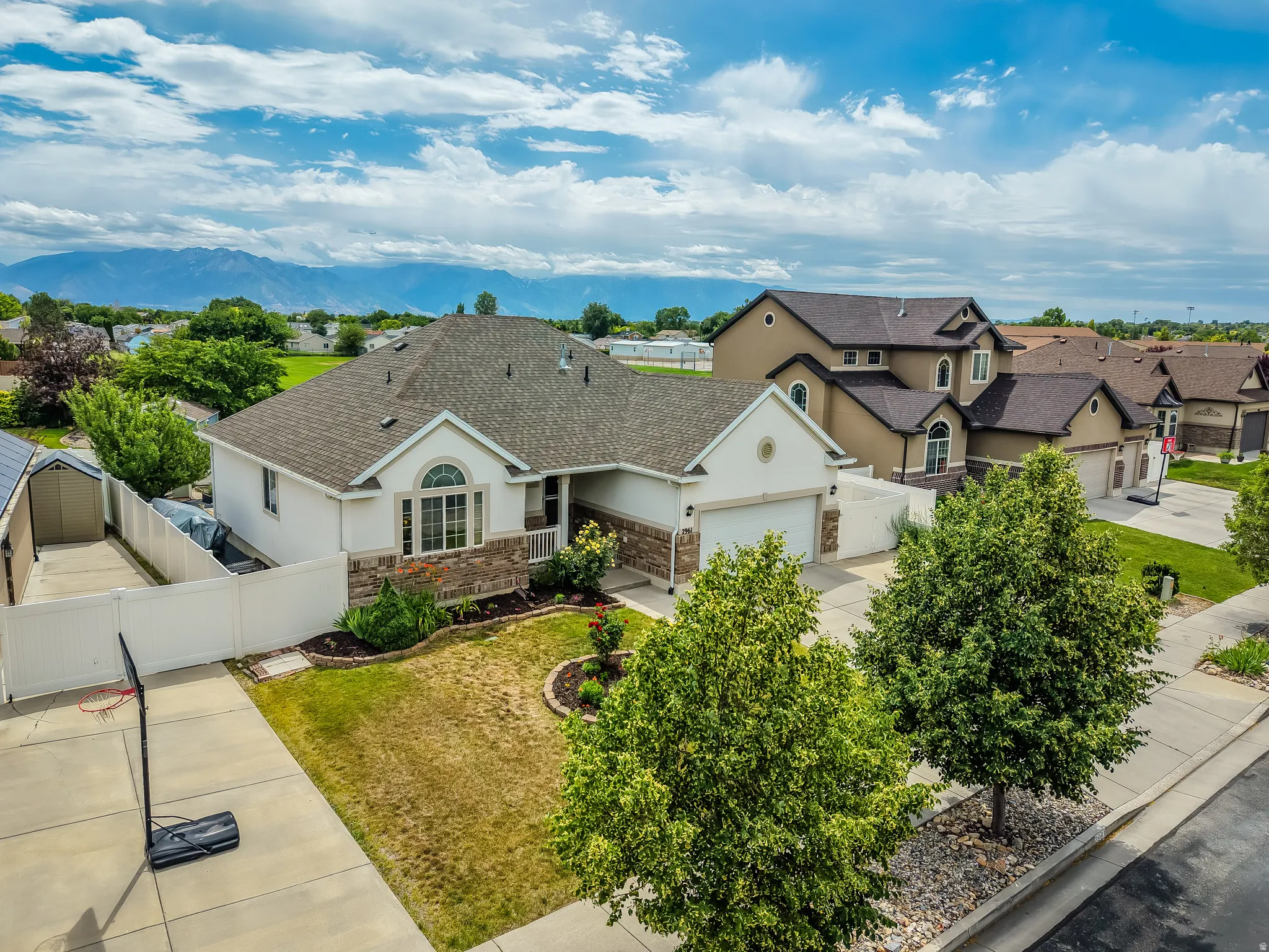 Single-story residence featuring a stone and stucco exterior, arched window details, an attached two-car garage, and a white privacy fence