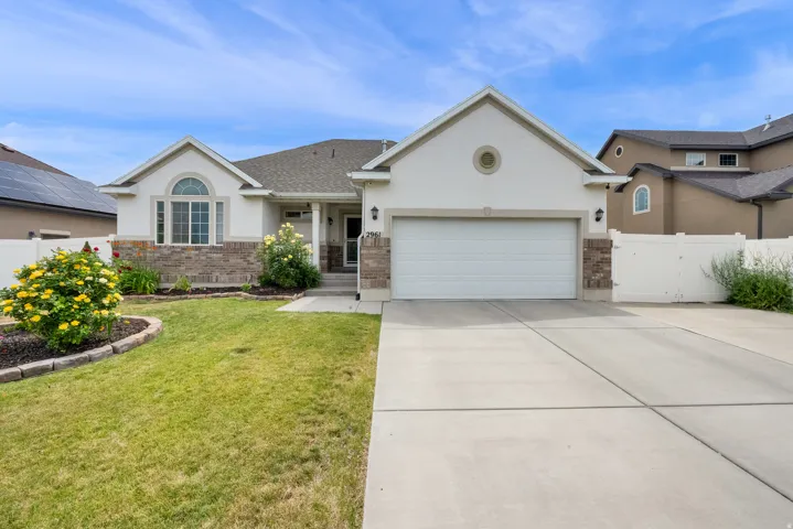 Single-story residence featuring a white exterior, stone accent detailing, and a prominent two-car garage