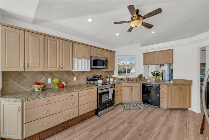 Kitchen featuring wood-finish flooring, light wood cabinetry, stone countertops, a tiled backsplash, and recessed lighting