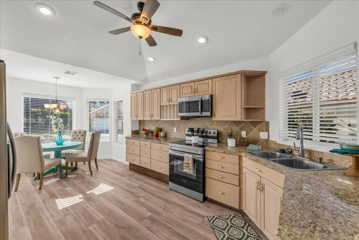 Kitchen and dining area featuring wood-finish flooring, light wood cabinetry, and granite-style countertops