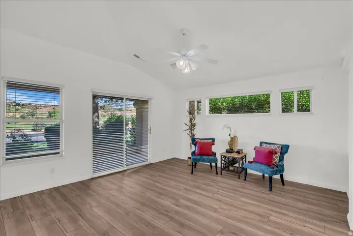 Spacious room featuring wood-finish flooring, a vaulted ceiling, and white painted walls