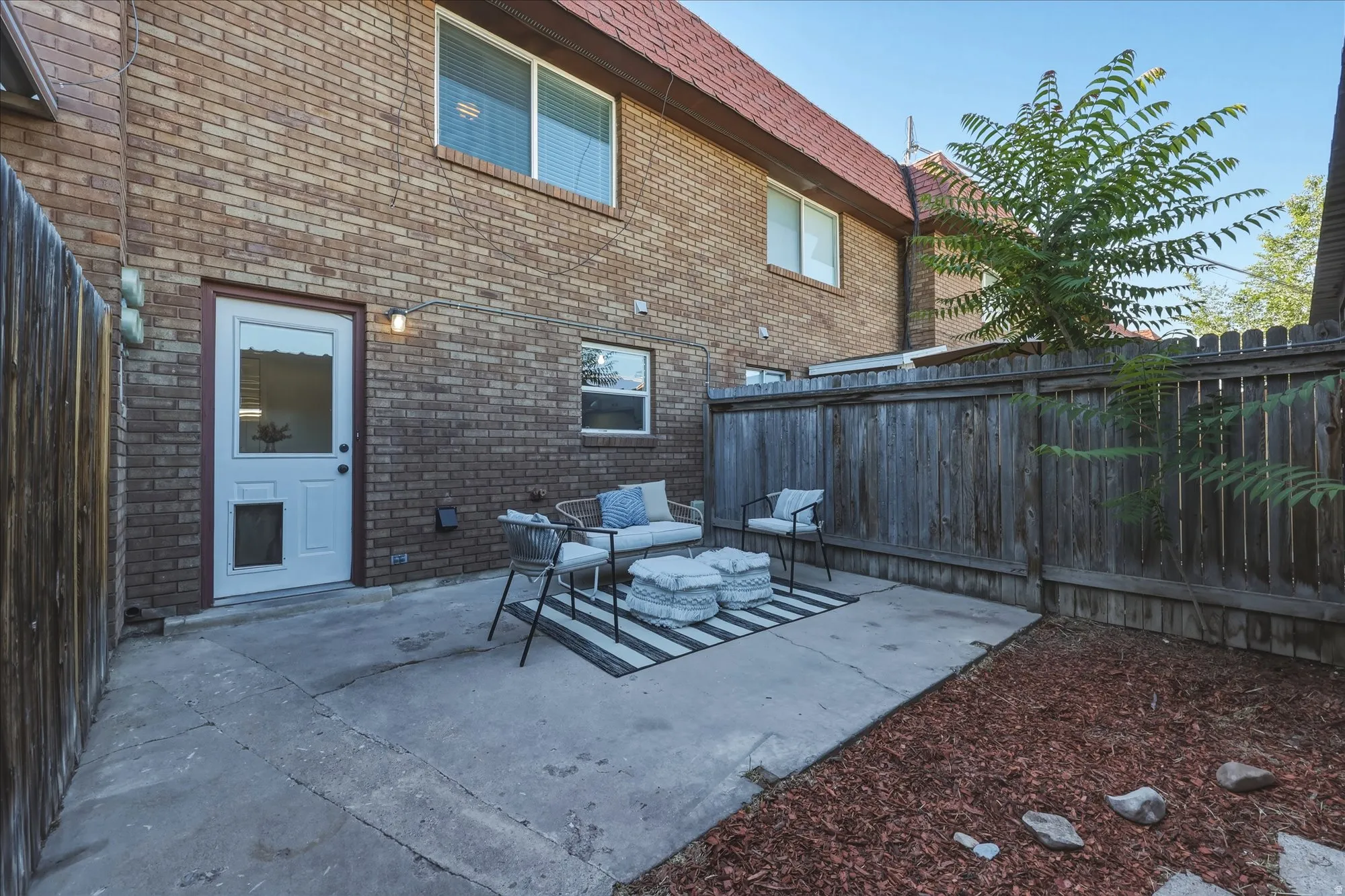 Private patio area featuring a concrete pad, a wooden privacy fence, and a mulched section