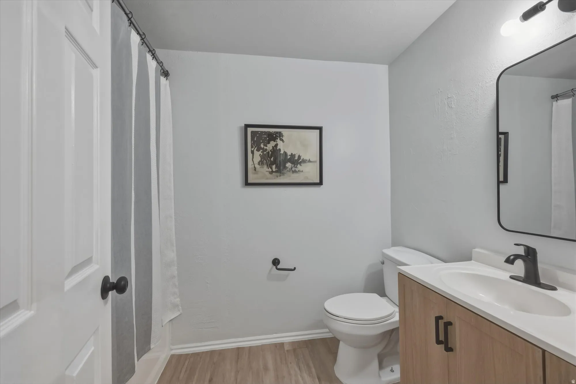 Modern bathroom featuring a wood-finish vanity with a white countertop and integrated sink