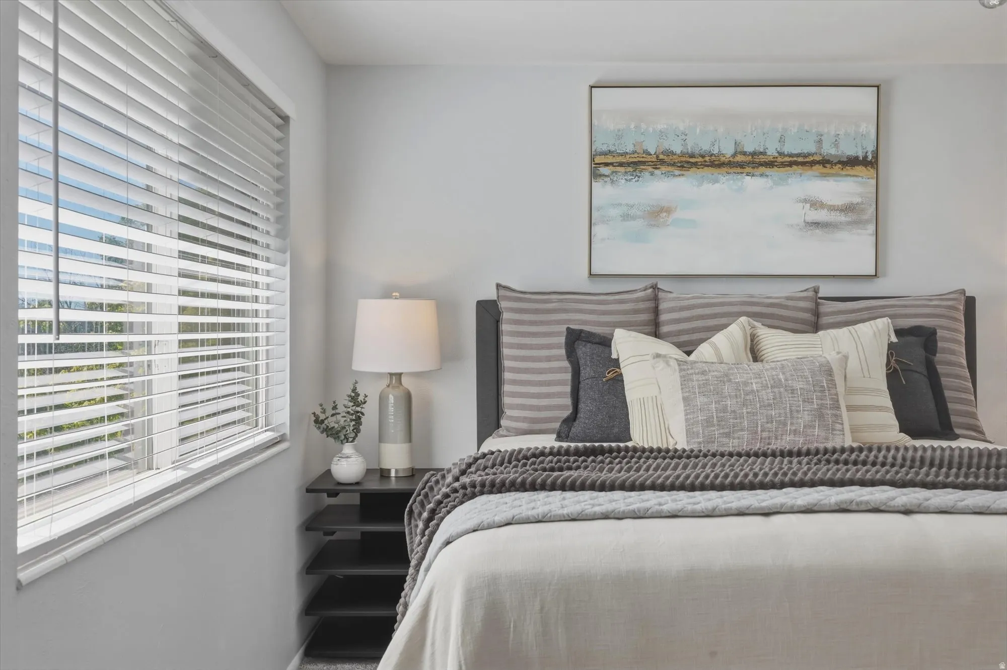 Spacious room featuring a large window with white horizontal blinds, light gray wall paint, and dark wood-finish flooring