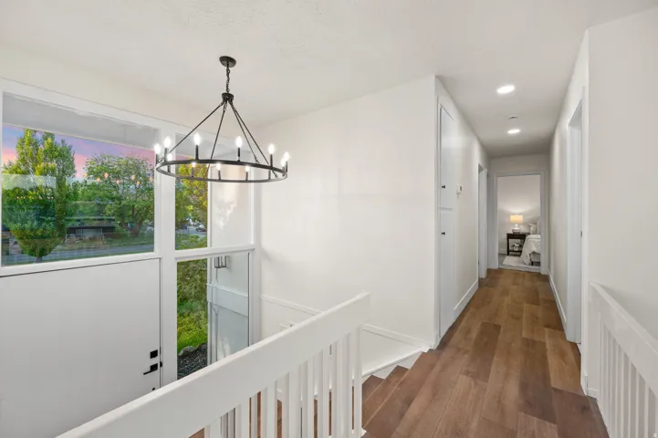 Upper-level hallway featuring wood-finish flooring, recessed lighting, and a modern chandelier