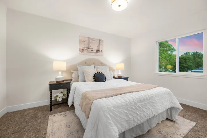 Bedroom featuring a tufted upholstered headboard, a large window, recessed lighting, and neutral carpeting
