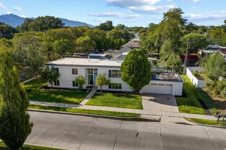 Mid-century modern exterior with white siding, an attached garage, and a flat roof
