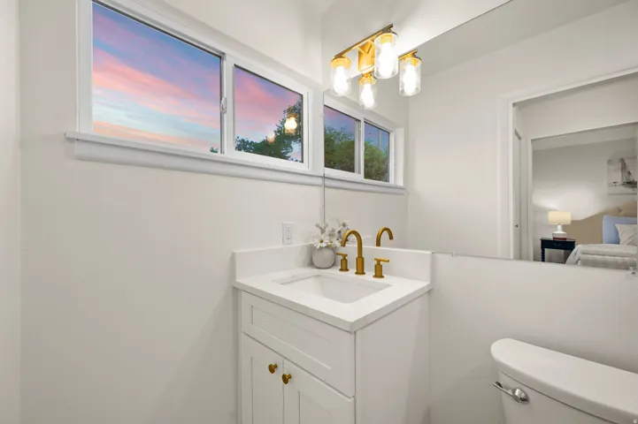 Bathroom featuring a white vanity with gold-tone hardware, a rectangular undermount sink, and a white countertop