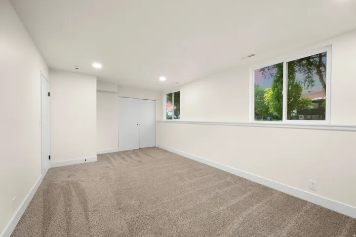 Spacious room with plush carpet flooring, recessed lighting, and white trim