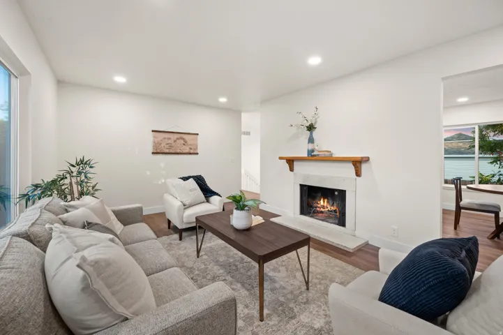 Living area featuring a stone fireplace with a wood mantle, recessed lighting, and wood-finish flooring
