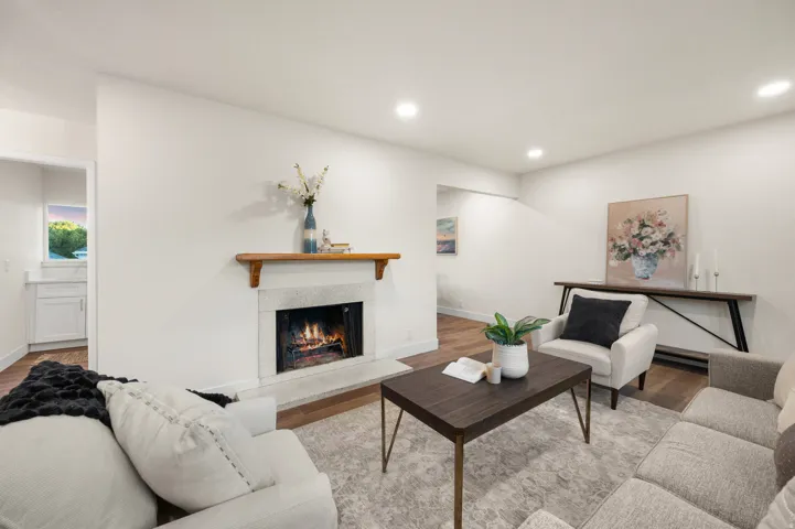 Living area featuring a stone-clad fireplace with a wood mantel, recessed lighting, and wood-finish flooring