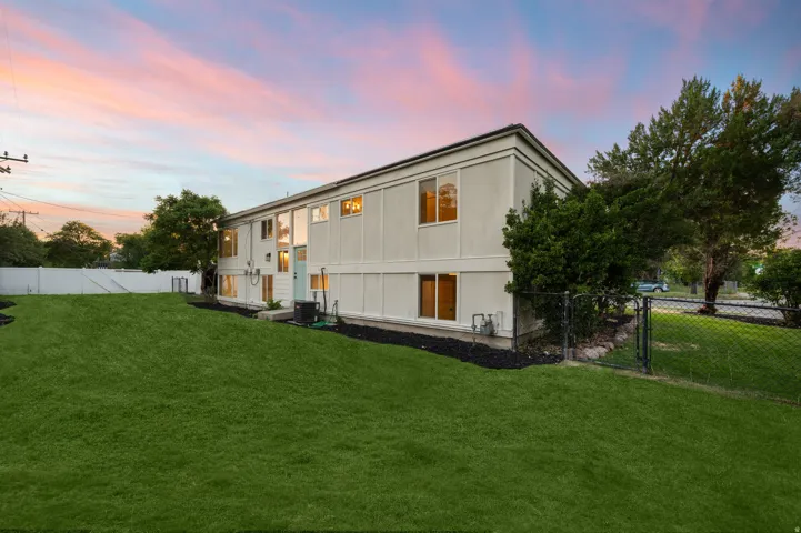 Expansive green lawn with a white privacy fence and chain link fencing