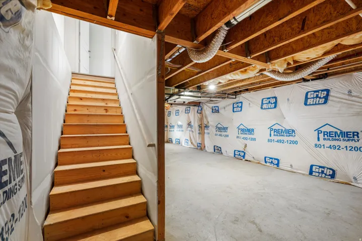 Unfinished basement featuring exposed wood joists, concrete flooring, and insulated walls