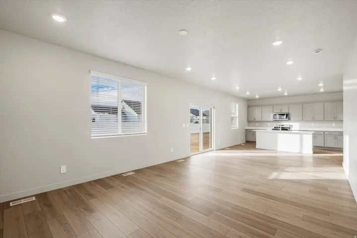 **DISCLAIMER** Interior package may vary. Open-concept living area with light wood-finish flooring, recessed lighting, and a large window with blinds