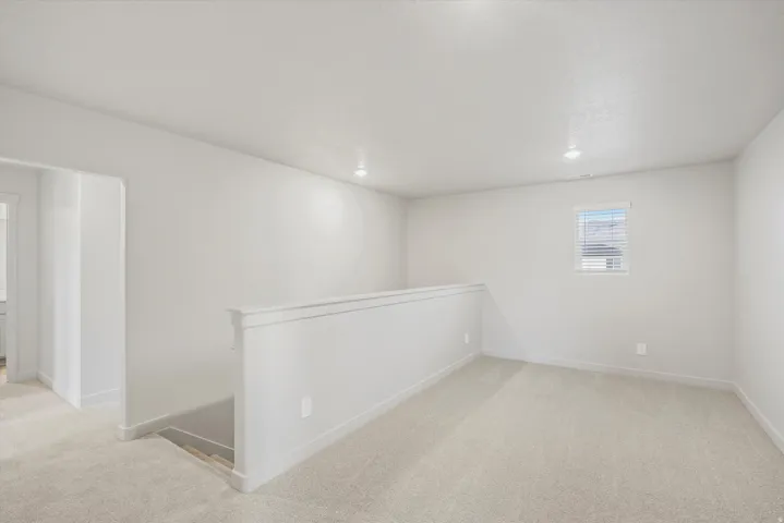**DISCLAIMER** Interior package may vary. Carpeted loft area featuring a white railing, recessed lighting, and a single window with horizontal blinds