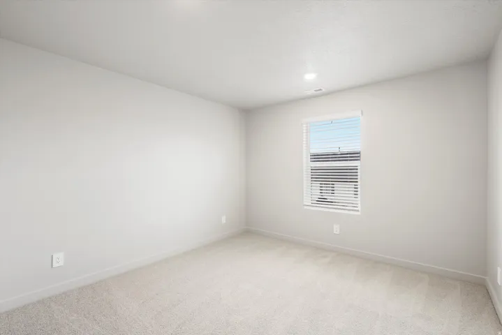 **DISCLAIMER** Interior package may vary. Neutral-toned room featuring light gray walls, plush carpet flooring, a window with white blinds, and recessed ceiling lighting
