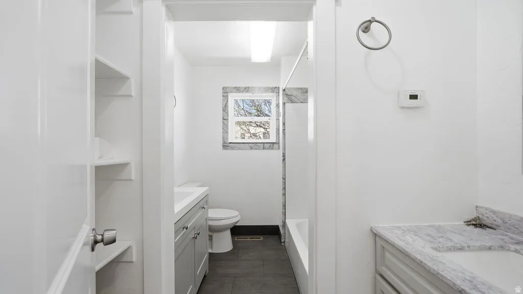 Bathroom featuring a white bathtub, toilet, and gray tiled flooring