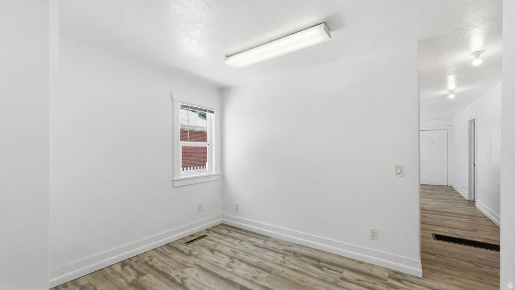 Room with light wood-finish flooring, white walls, and white trim