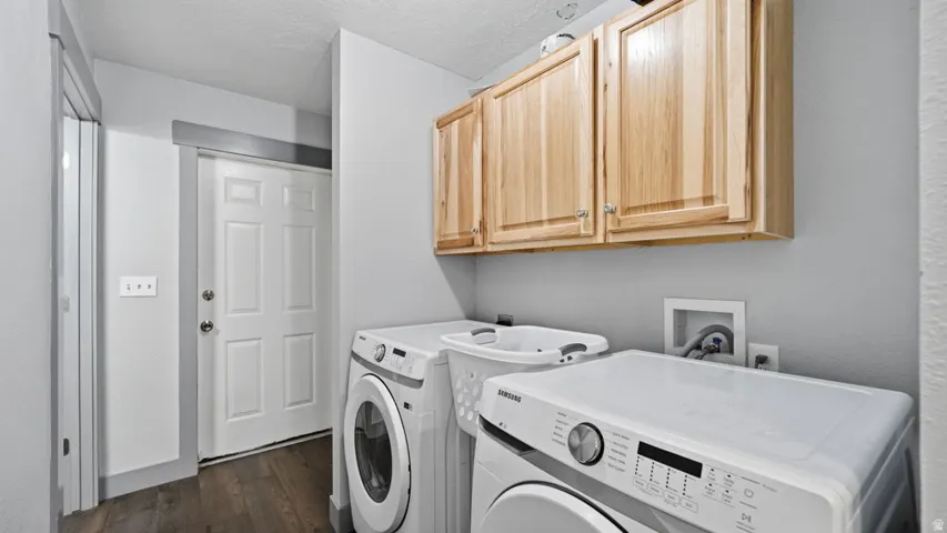 Dedicated laundry area featuring wood-finish flooring, light gray walls, and natural wood cabinetry