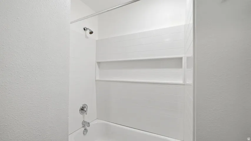White subway tile shower surround featuring an integrated niche