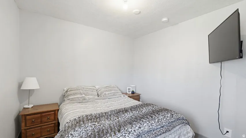 Bedroom featuring light gray walls, textured ceiling, recessed lighting, and a wall-mounted television
