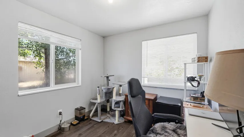 Bright interior space with two windows, light gray wall paint, wood-finish flooring, and a recessed ceiling light