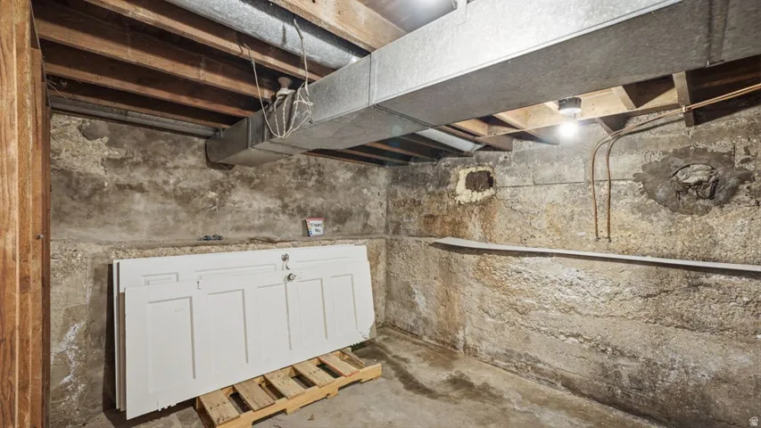 Unfinished basement featuring exposed joists, concrete walls, and visible ductwork