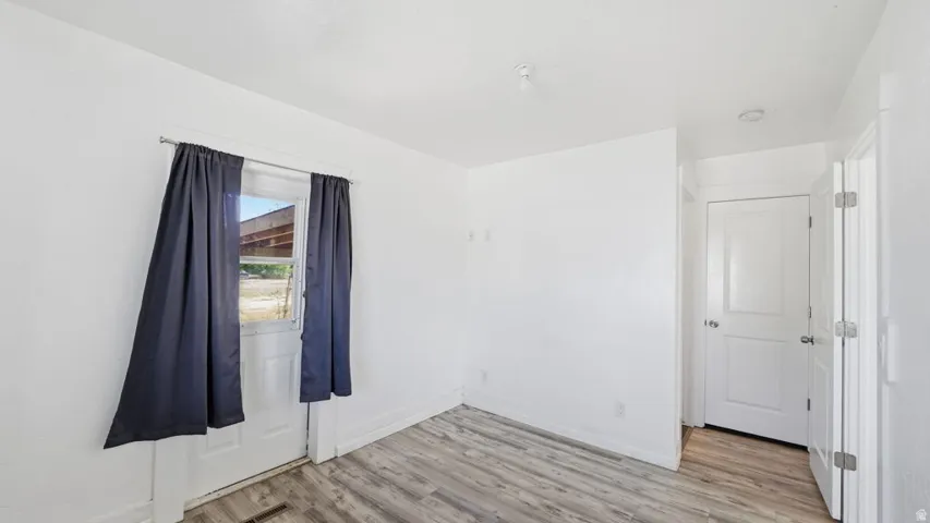 Bright interior space featuring wood-finish flooring, white walls, and a white paneled door