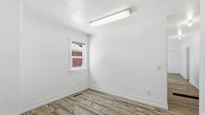 Room with light wood-finish flooring, white walls, and white trim