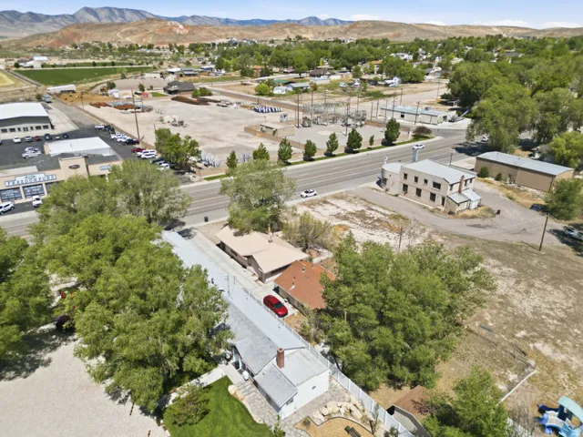 Aerial perspective showcasing a residential property with a partial green lawn, surrounded by mature trees