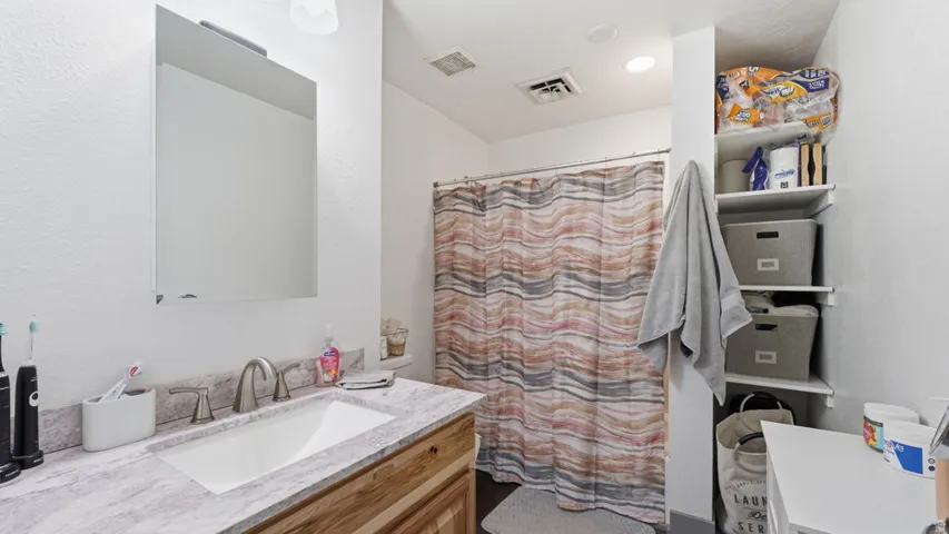 Bathroom featuring a wood-finish vanity with a built-in sink and a light-toned countertop