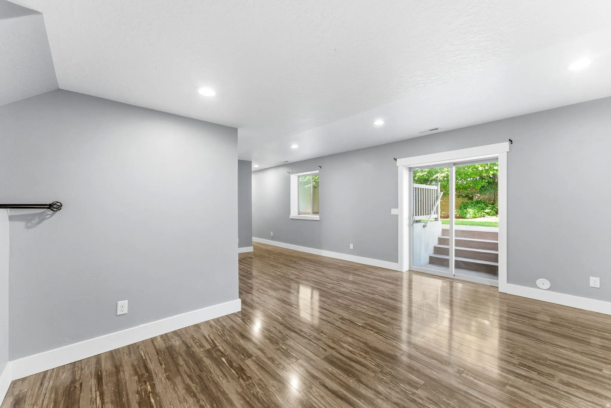 Spacious room featuring wood-finish flooring, light gray walls, and white trim throughout