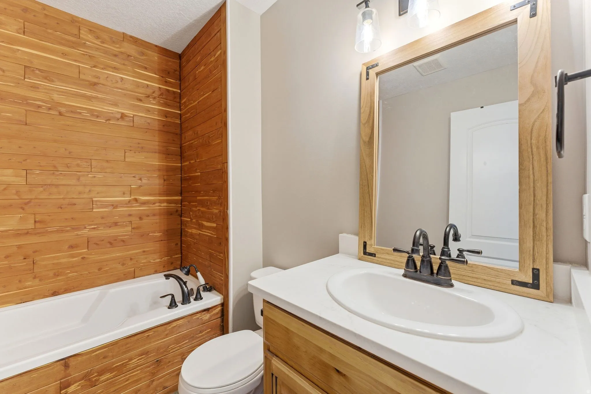 Bathroom featuring a single vanity with a white countertop, an undermount sink, and a dark bronze faucet