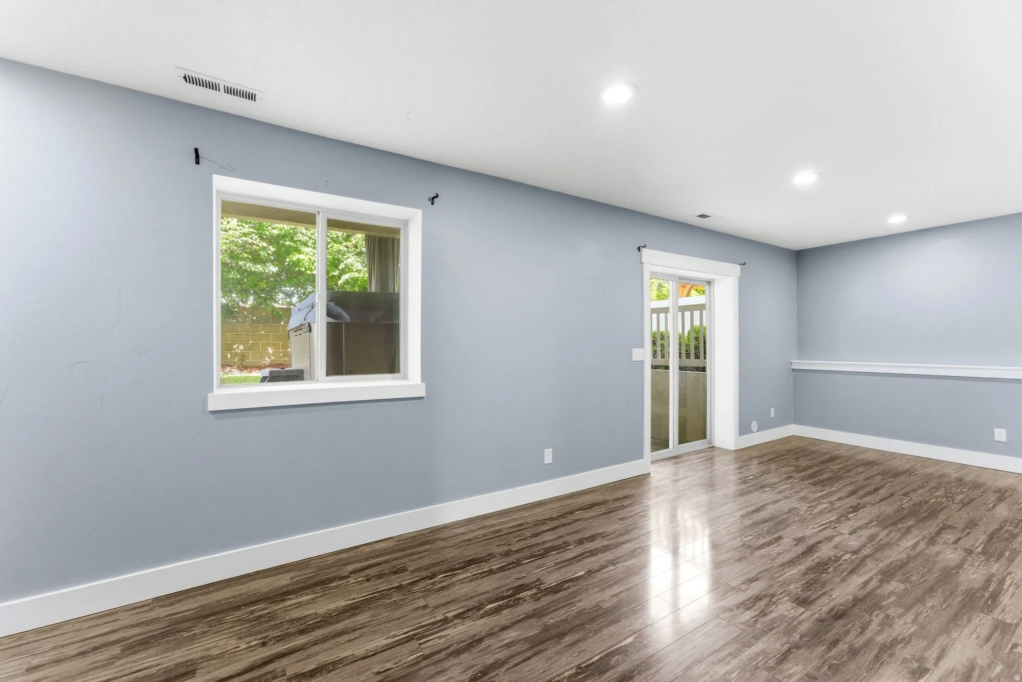 Spacious interior featuring wood-finish flooring, light blue walls, and white trim