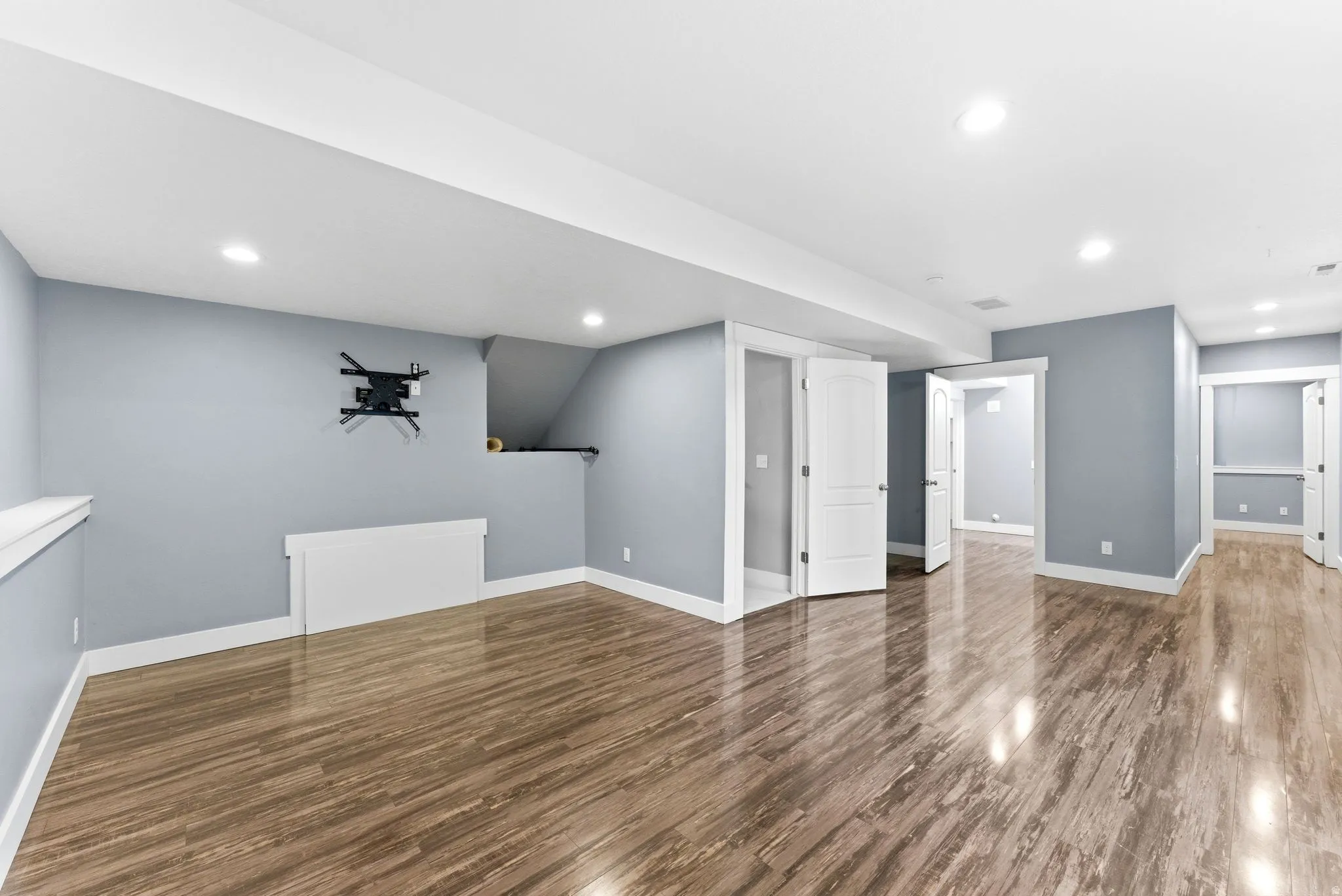 Additional living room featuring wood-finish flooring, recessed lighting, neutral wall tones, white trim, and multiple doorways