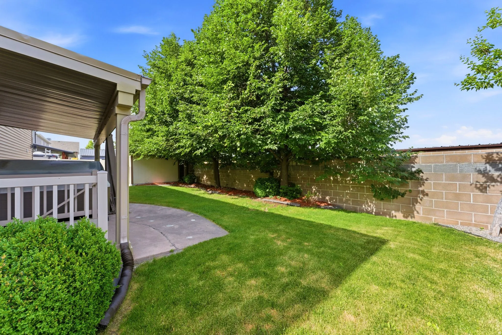 Covered patio featuring a railing, a paved patio area, and a lush lawn