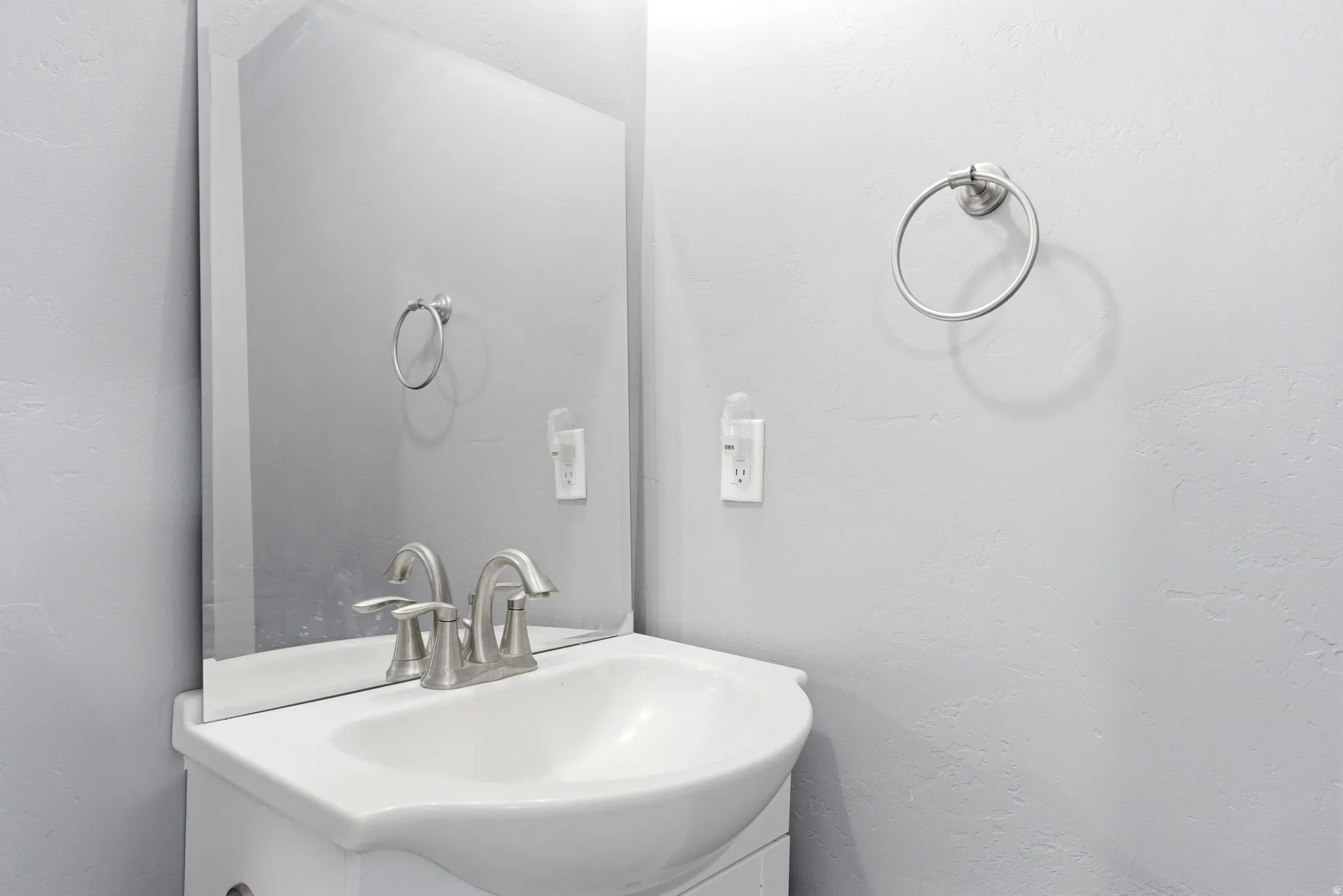 Pedestal sink with a brushed nickel faucet, framed by a wall-mounted mirror