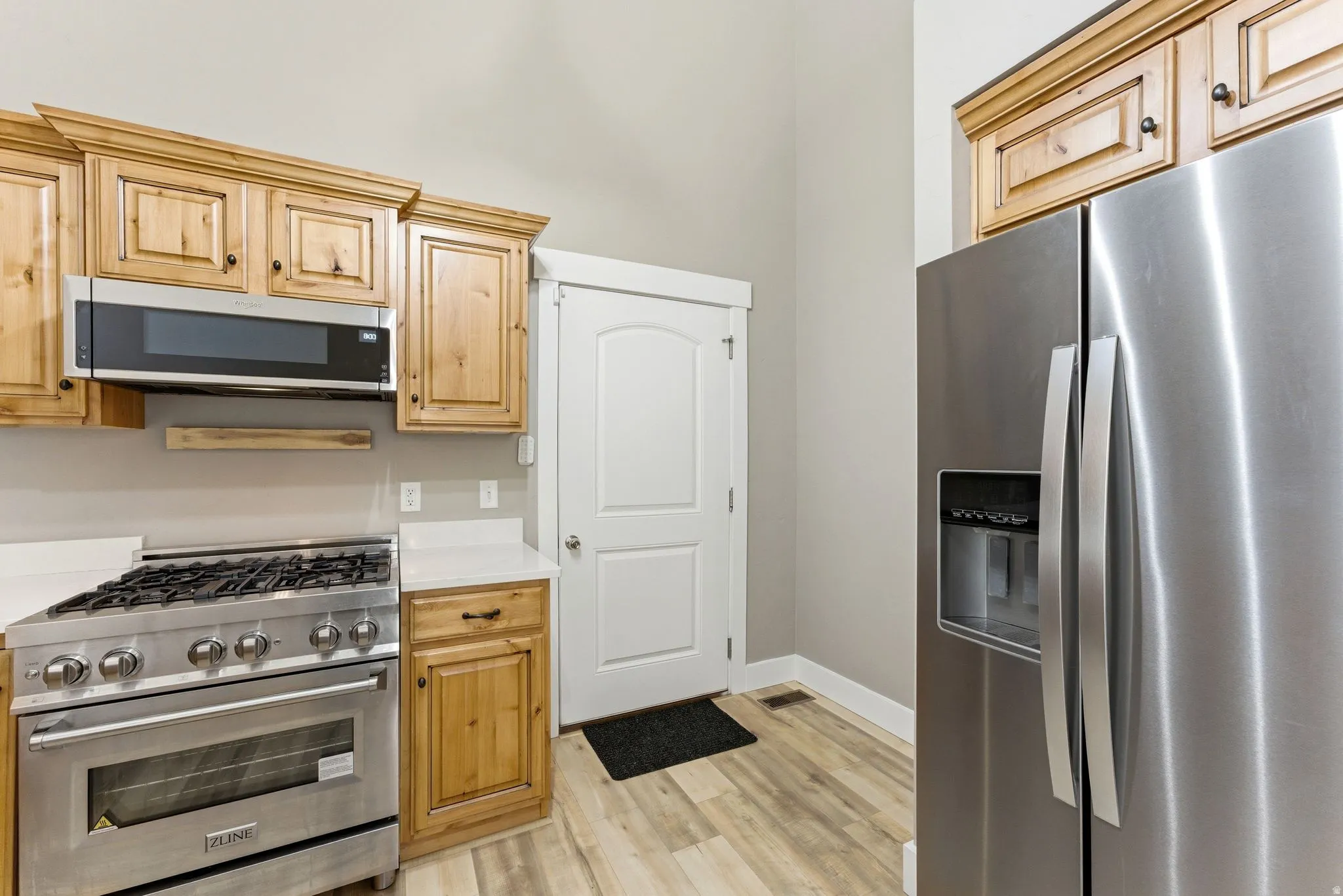 Kitchen featuring stainless steel appliances, wood-finish cabinetry, white countertops, and new LVP flooring.